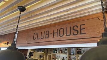 Un letrero de madera con la palabra 'CLUB-HOUSE' colgando del techo.