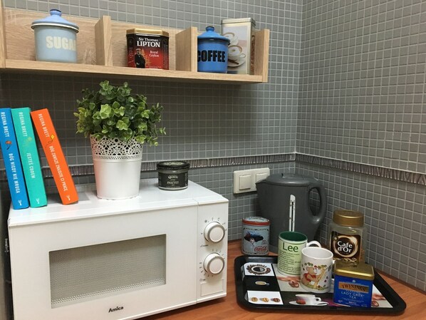 A kitchen area with a microwave, a coffee maker, and various kitchen items on the counter. - Arcus Premium Hostel (Warsaw)