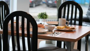 A dining area with a table and chairs, a coffee cup, and a plate with food. - Arcus Premium Hostel (Warsaw)