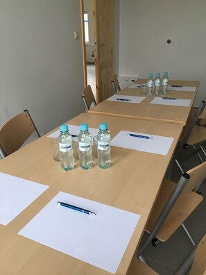 A conference room with a long table, chairs, water bottles, and pens on the table. - Arcus Premium Hostel (Warsaw)