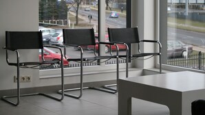 Three black chairs with metal frames in a modern room with a large window. - Arcus Premium Hostel (Warsaw)