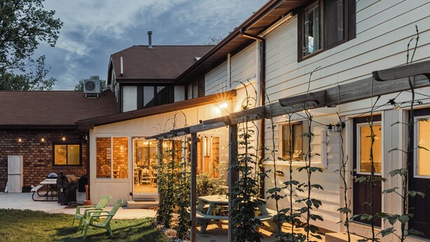 Et hus med overdækket terrasse, udendørs møbler og en murstensfacade.