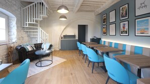 A cozy restaurant with a stone wall, a staircase, and blue chairs. - Botrona B&B (Scarlino)