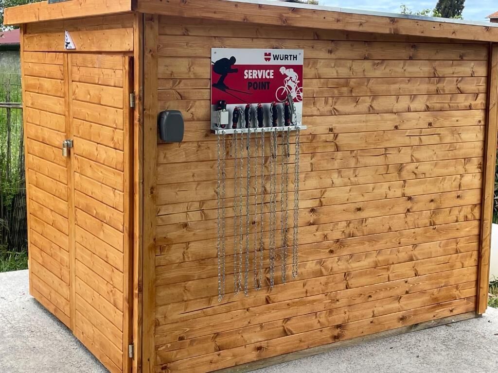 Eine hölzerne Konstruktion mit einem Schild, das einen Servicepunkt kennzeichnet, Ketten, die an der Wand hängen, und einer Tür.