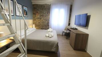 Ein Schlafzimmer mit Bett, Schreibtisch, Fernseher und einer Treppe.
