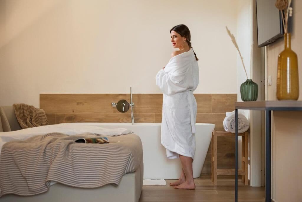 Ein Schlafzimmer mit einem Bett, einem Holz-Kopfteil, einer Badewanne und einem kleinen Holzhocker.