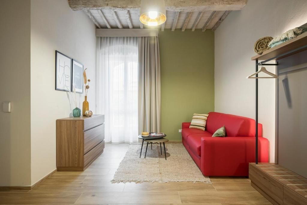 Una sala acogedora con un sofá rojo, un armario de madera y un perchero.