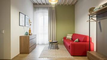 Una sala acogedora con un sofá rojo, un armario de madera y un perchero.
