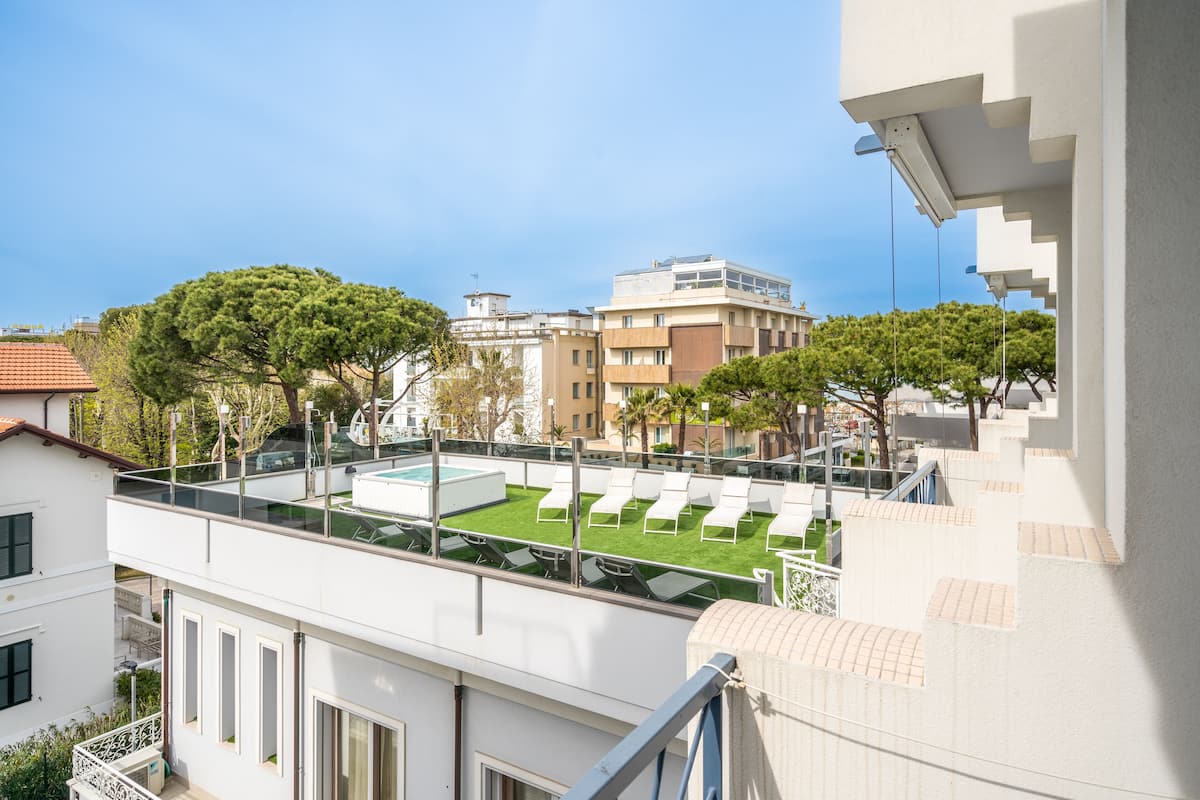 Terraza en la azotea con piscina, sillas de descanso y vistas de edificios circundantes.