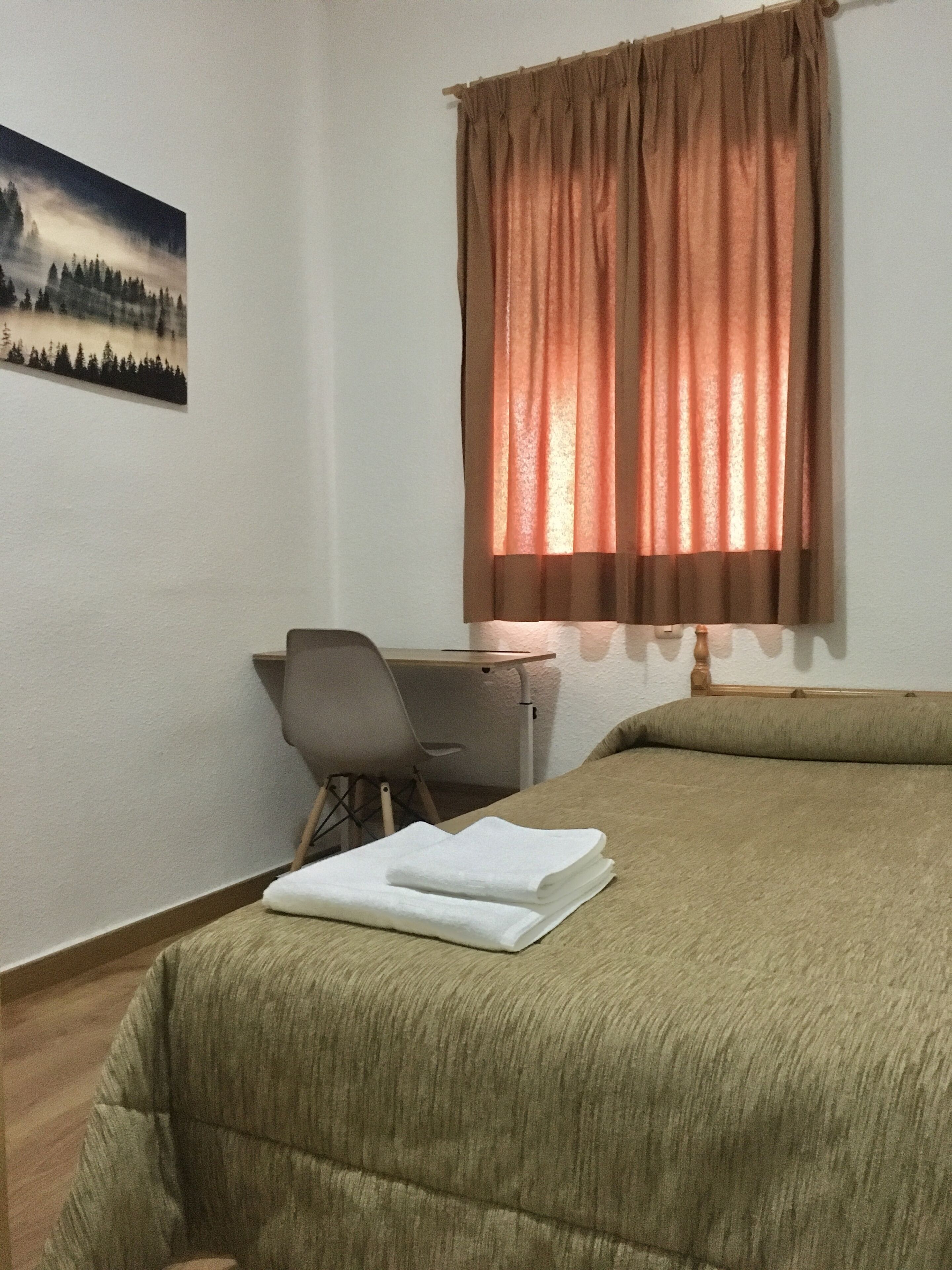 A room with a bed, a desk, and a chair.