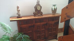 A wooden cabinet with multiple drawers, a decorative clock, and a vase on top. - Hostal Santa Bárbara (Toledo)