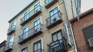 A multi-story building with a "HOSTAL" sign, featuring balconies and barred windows. - Hostal Santa Bárbara (Toledo)