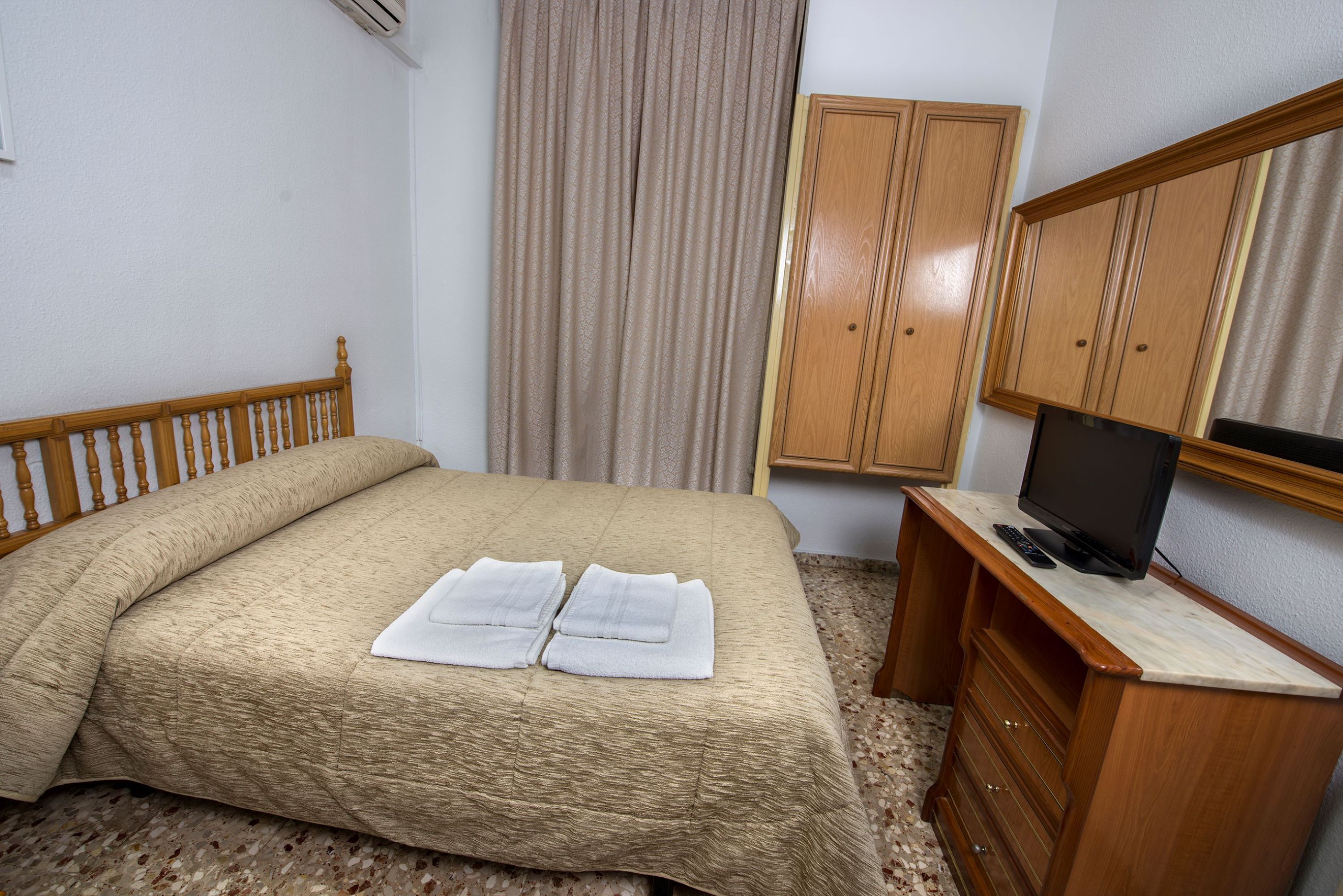 Une chambre d’hôtel comprenant un lit, un bureau avec une télévision et une armoire.