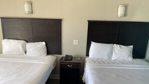 A hotel room with two beds, each with white linens and dark headboards. There is a small bedside table with a telephone and a glass on it. - Express Inn West Memphis (West Memphis)