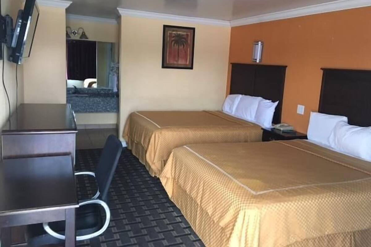 A hotel room with two beds, a desk, and a TV.