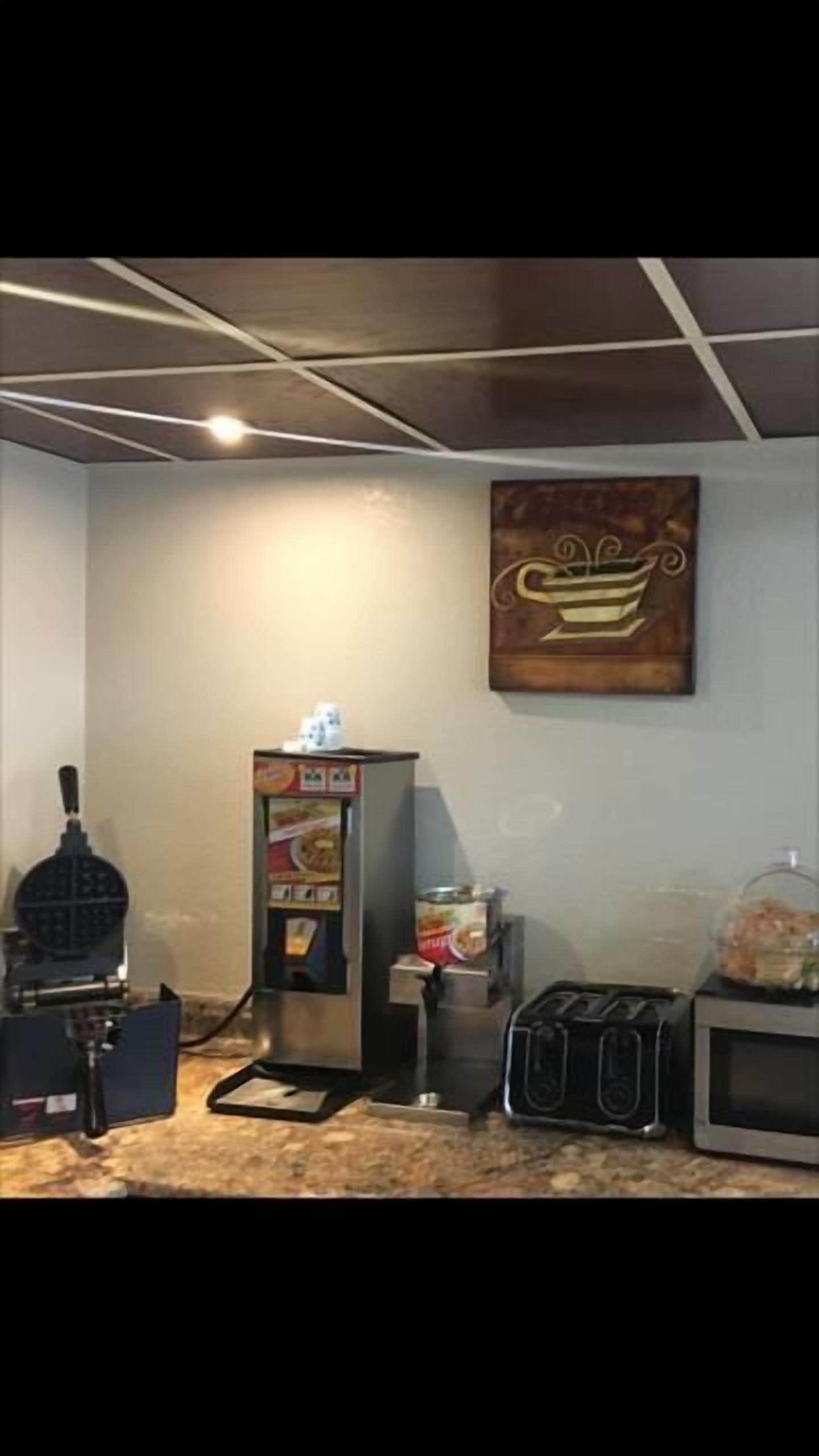 A kitchenette with a coffee machine, a toaster, a microwave, and a refrigerator.