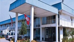 A modern building with a blue roof and white walls, featuring a covered entrance and a flag. - Express Inn West Memphis (West Memphis)