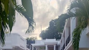 A grand staircase leading to a white building with balconies, surrounded by palm trees. - SAMS Hotel (Port-au-Prince)