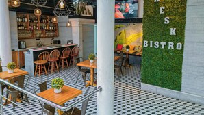 A cozy bistro with a bar area, wooden tables, and chairs. - SAMS Hotel (Port-au-Prince)