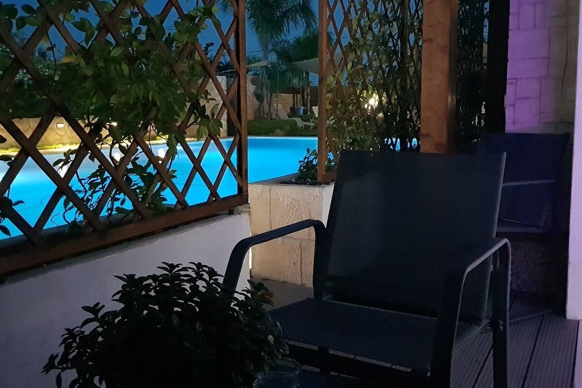 Ein Balkon mit Pool, einem Stuhl und Topfpflanzen.