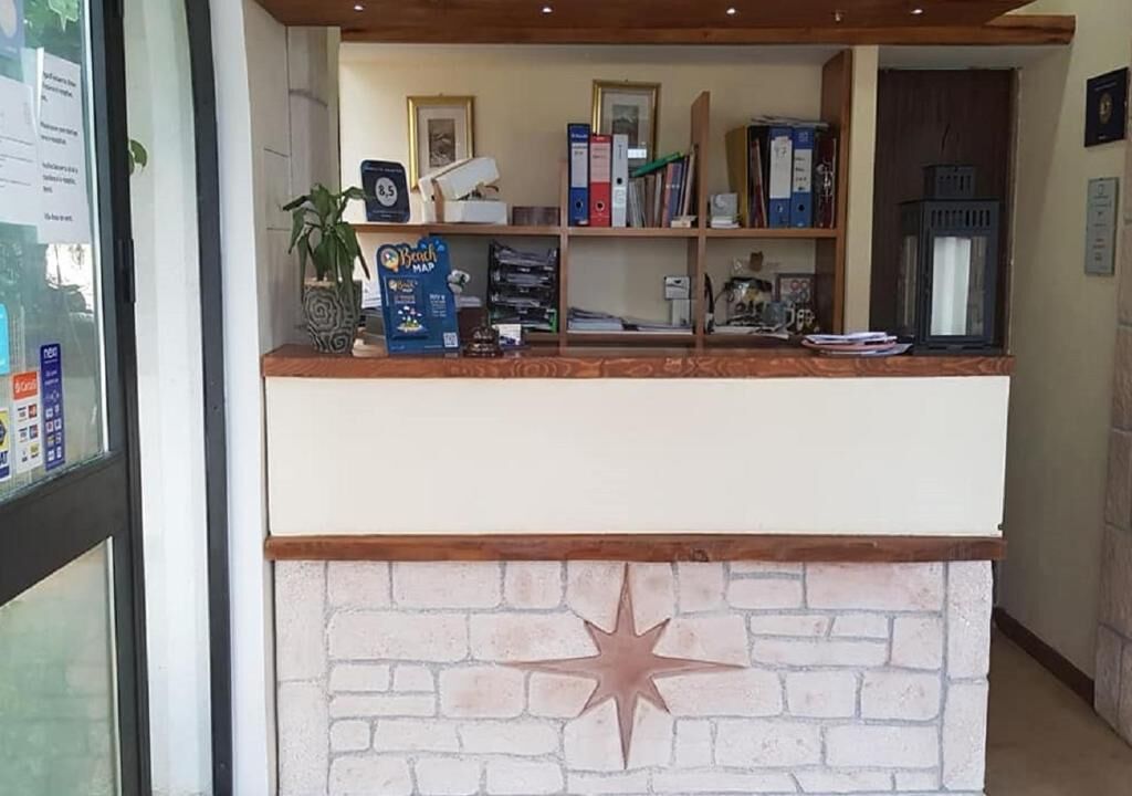A reception desk with a brick wall design, a star decoration, and various items like a plant, a map, and binders.