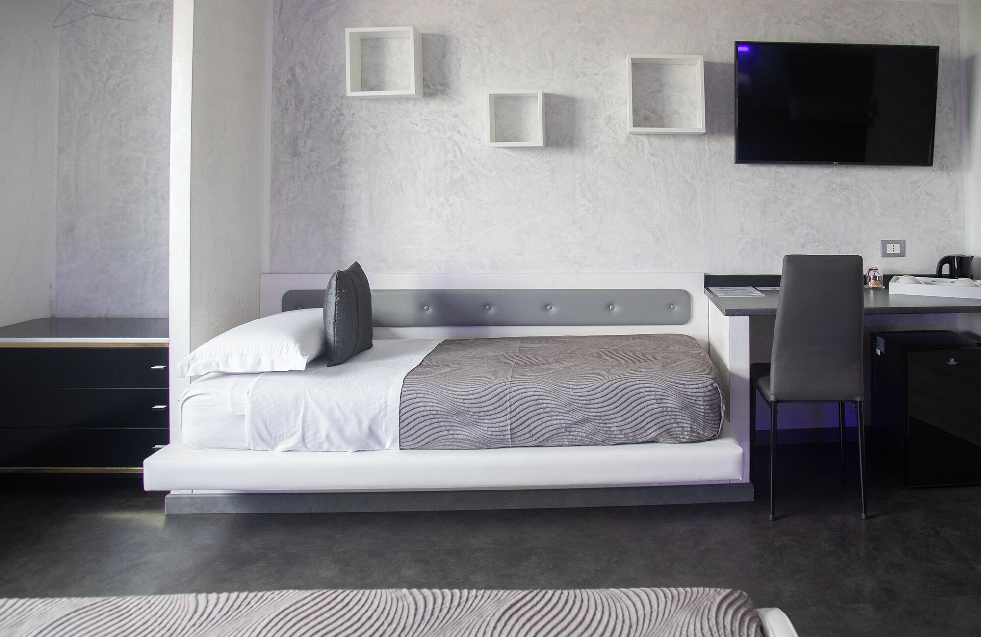 Una habitación de hotel moderna con cama, escritorio y televisión.