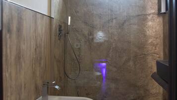 Un baño moderno con una bañera blanca grande, un inodoro separado y una zona de ducha.