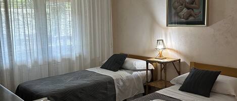Una habitación de hotel con dos camas, un escritorio, una lámpara y una luz en el techo.