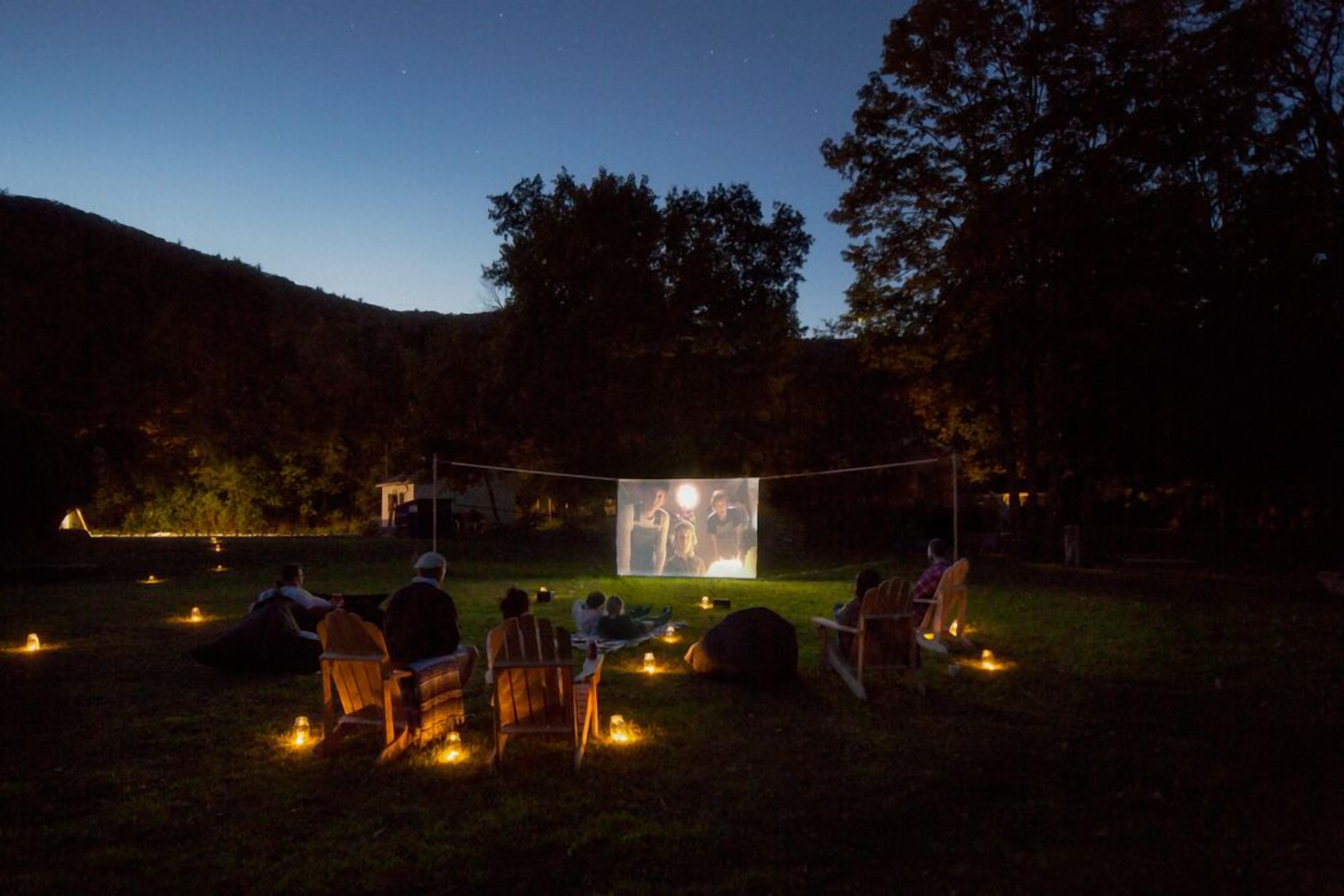 An outdoor movie screening with a clear screen and chairs arranged in a semi-circle.