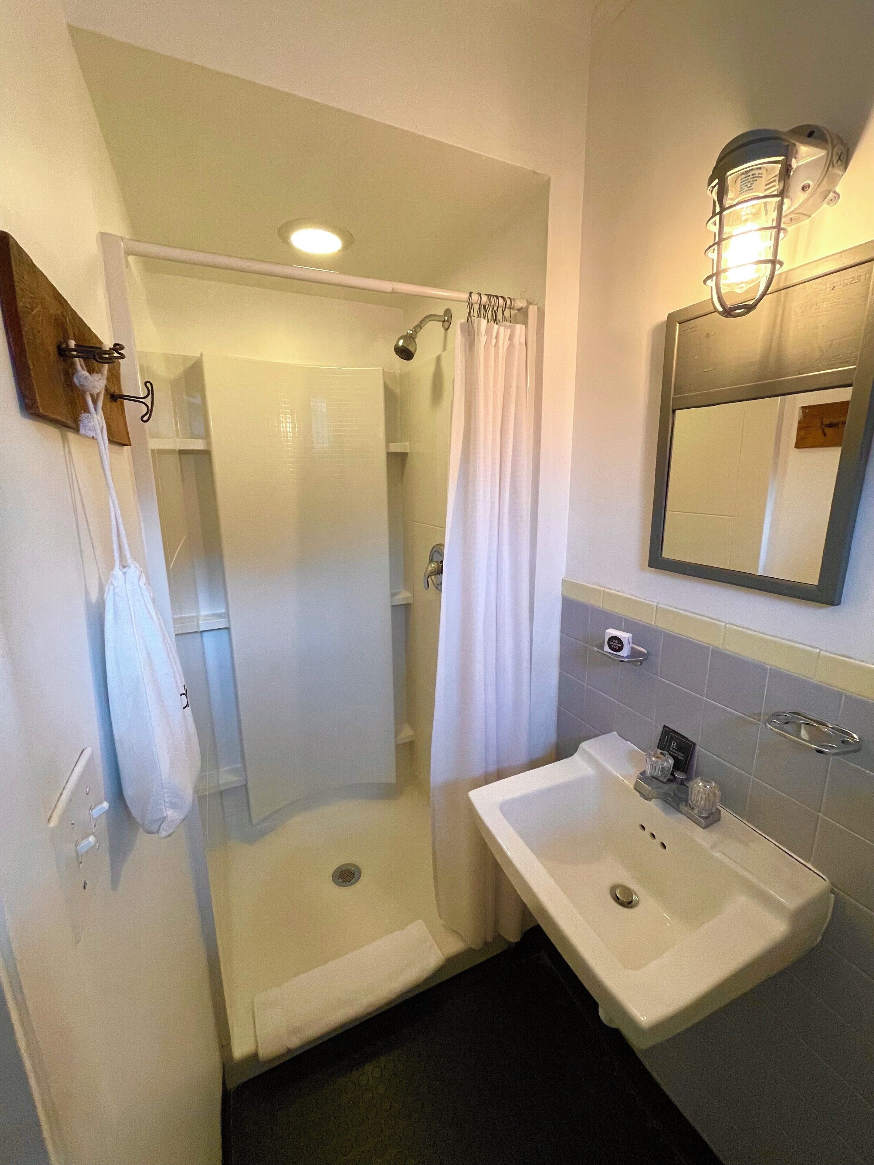 Ein Badezimmer mit Dusche, Waschbecken und Spiegel.