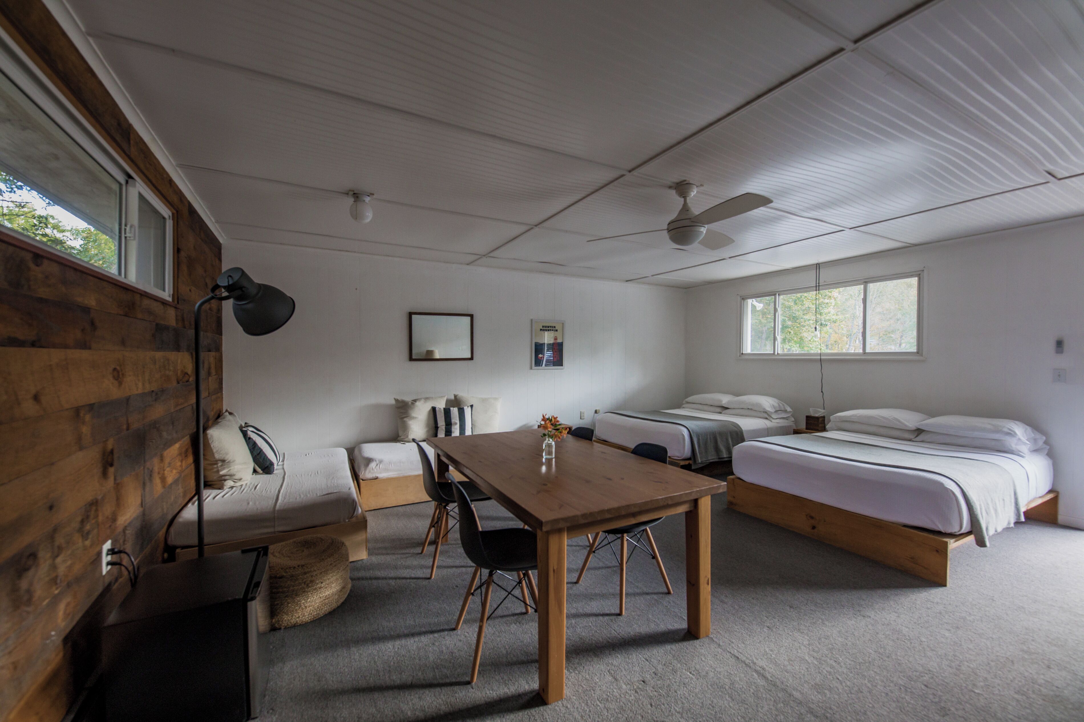 A room with a wooden wall, a bed, a desk, and a chair.