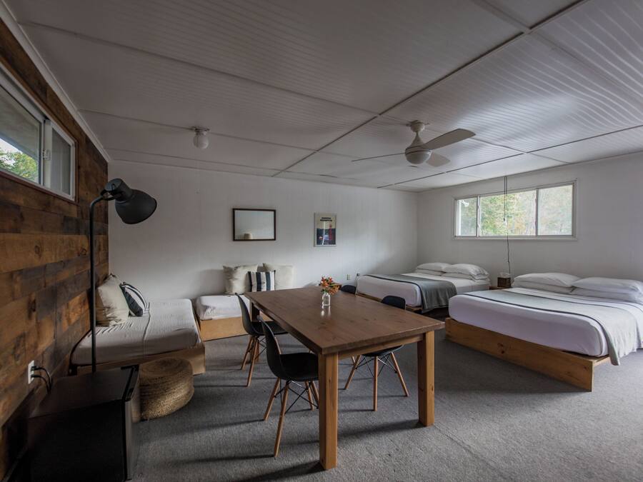 Quarto com parede de madeira, uma cama, uma escrivaninha e uma cadeira.