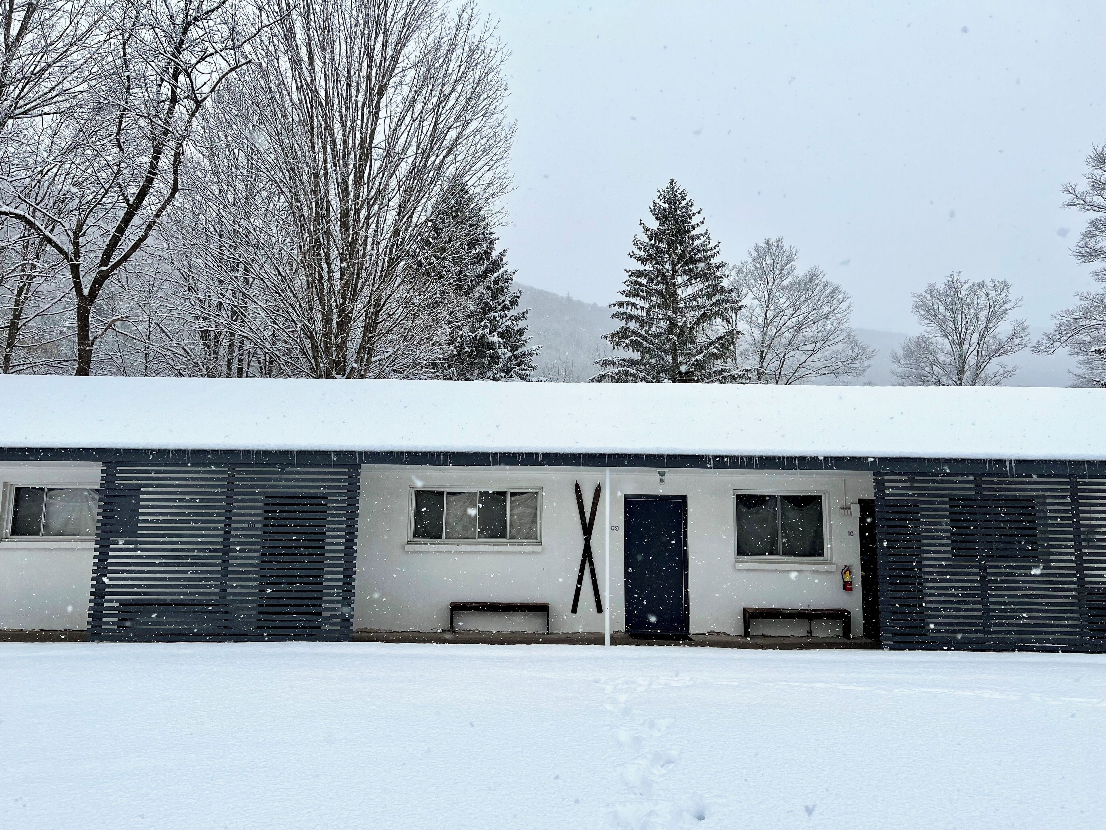 Un edificio con techo nevado y una gran estructura en forma de X al frente.