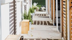 A corridor with white walls, wooden slats, and a concrete floor. - The Graham & Co. (Phoenicia)