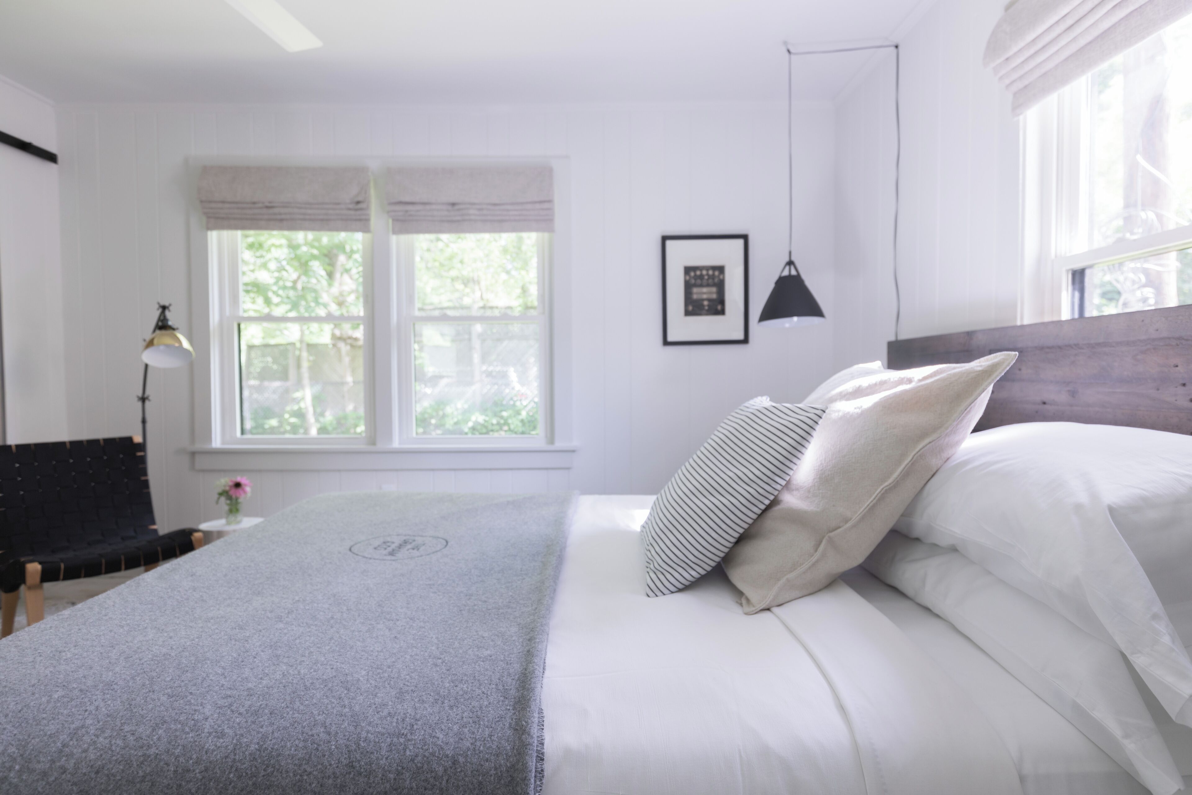 A bedroom with a bed, a bench, a lamp, and a window with curtains.