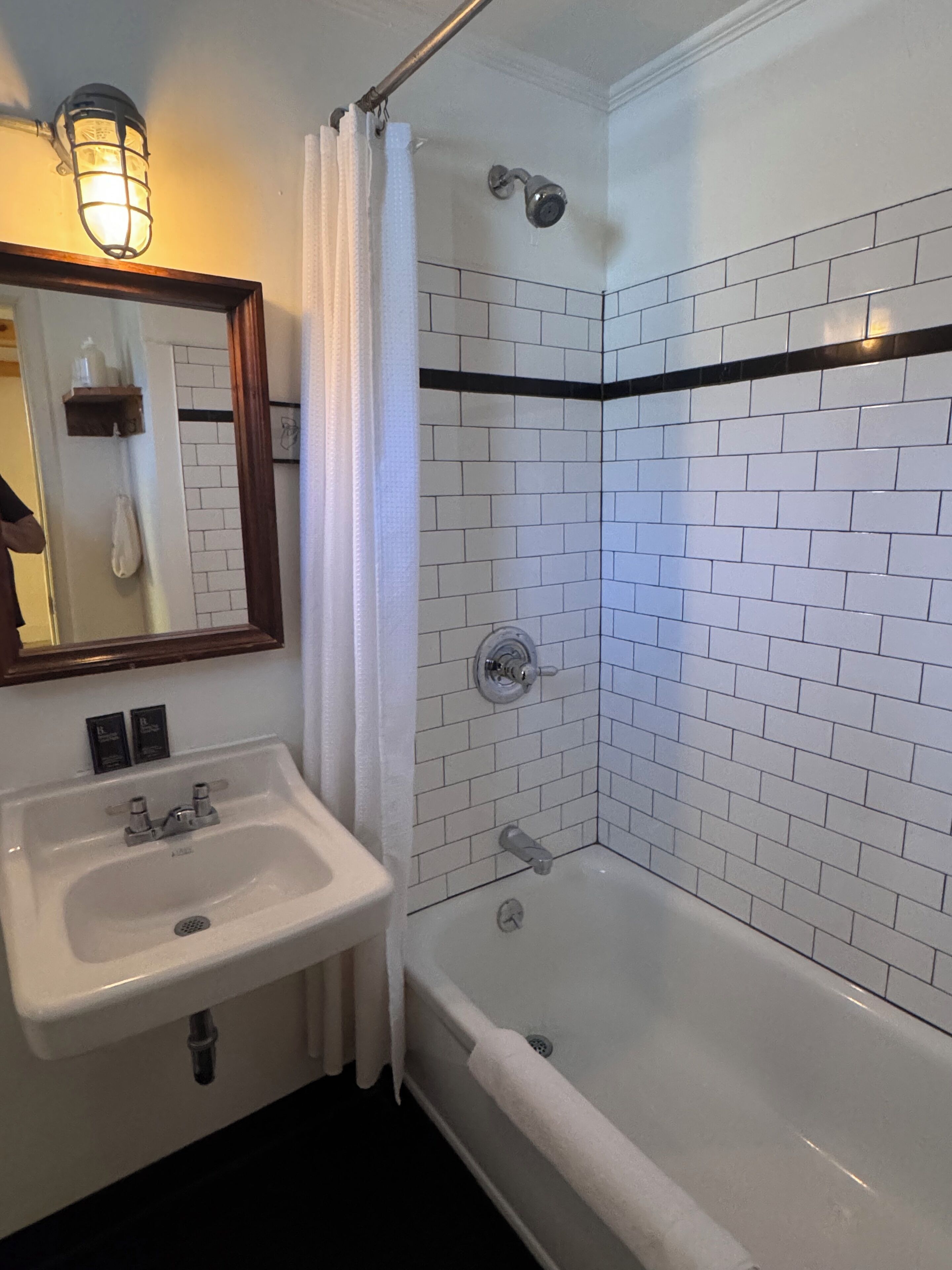 A bathroom with a white sink, a bathtub, and a shower with a black accent wall.