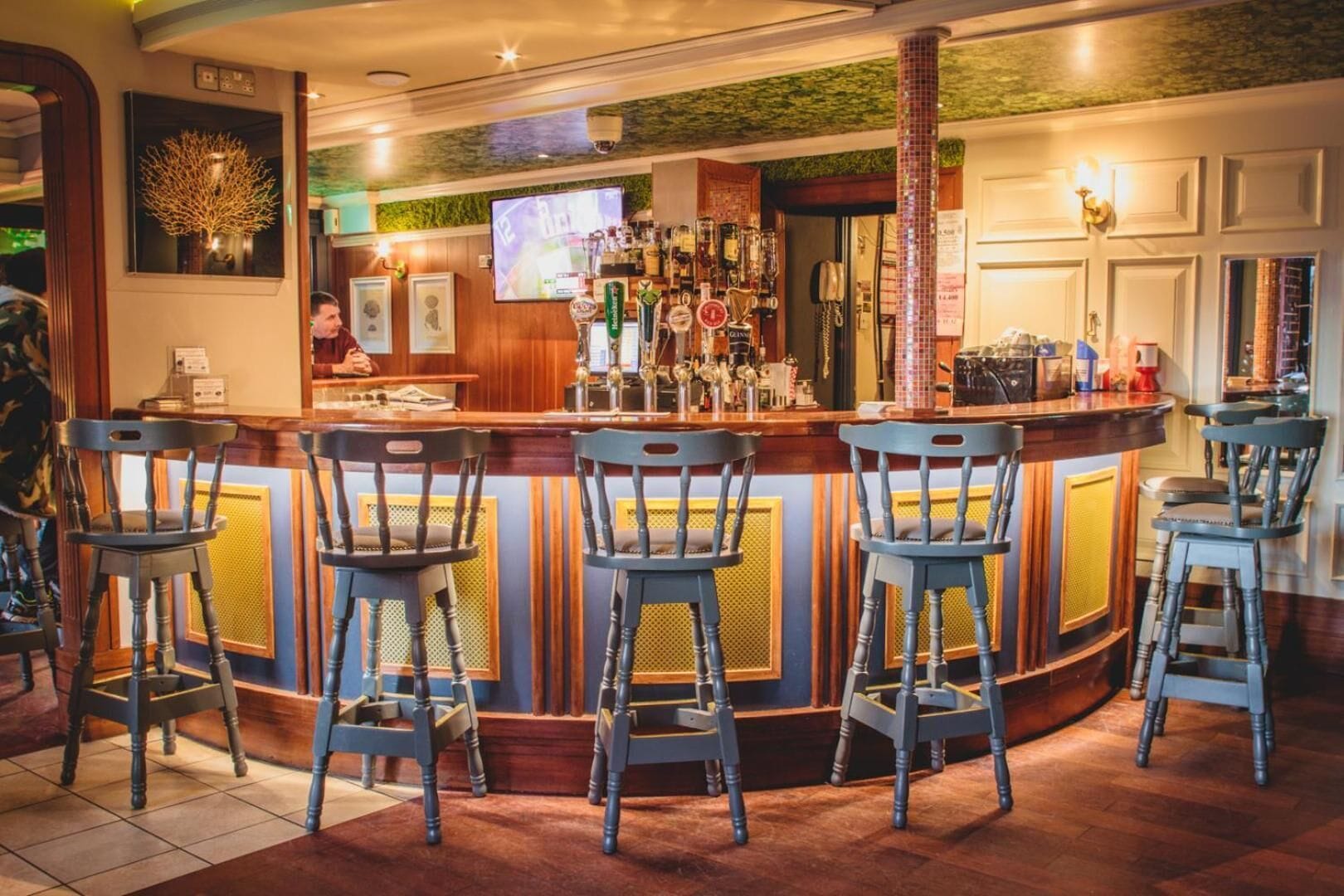 Un'area bar con un bancone, sgabelli e uno schermo televisivo.