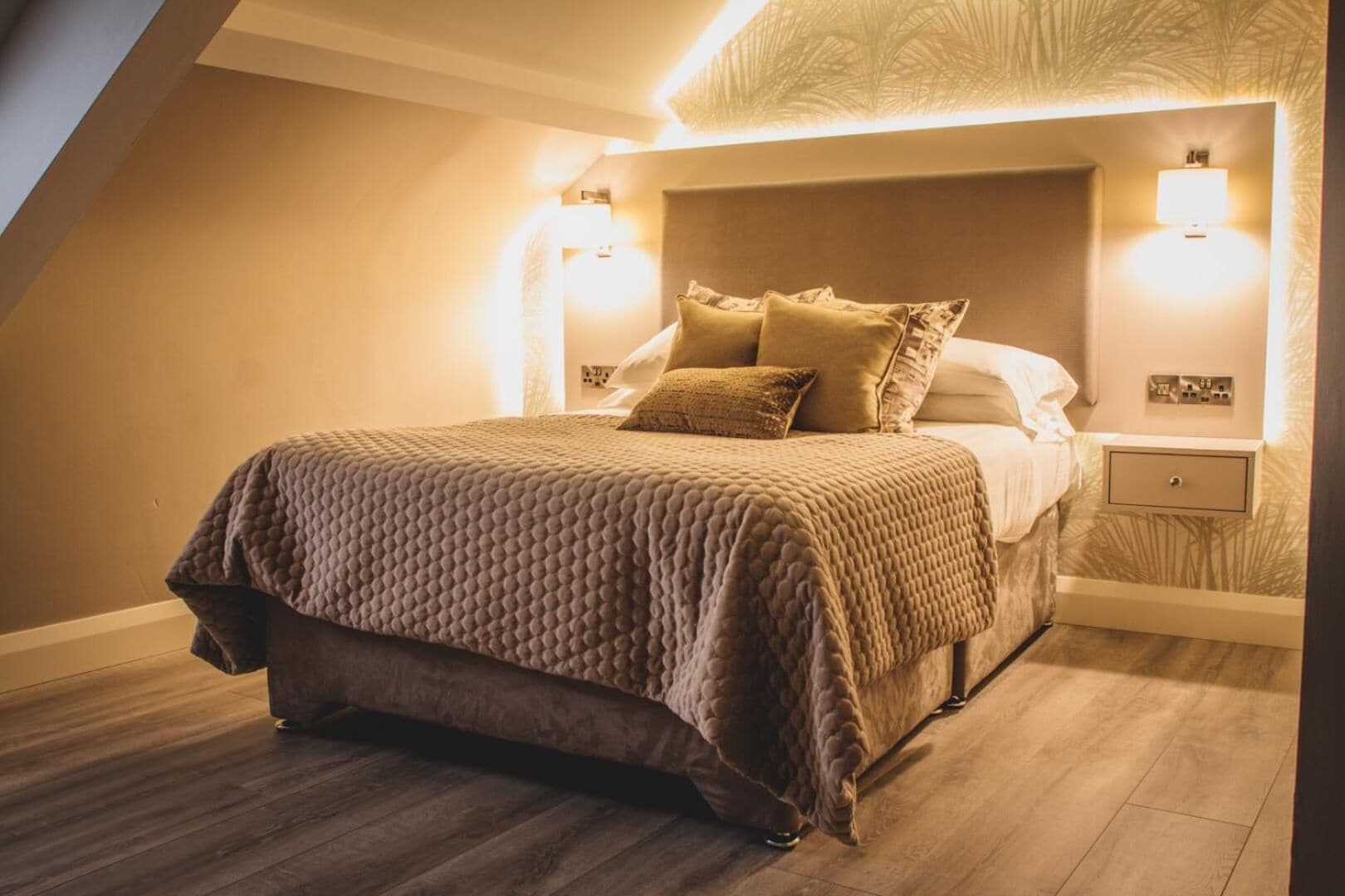 Un dormitorio con una cama grande, una mesita de noche y lámparas de pared.