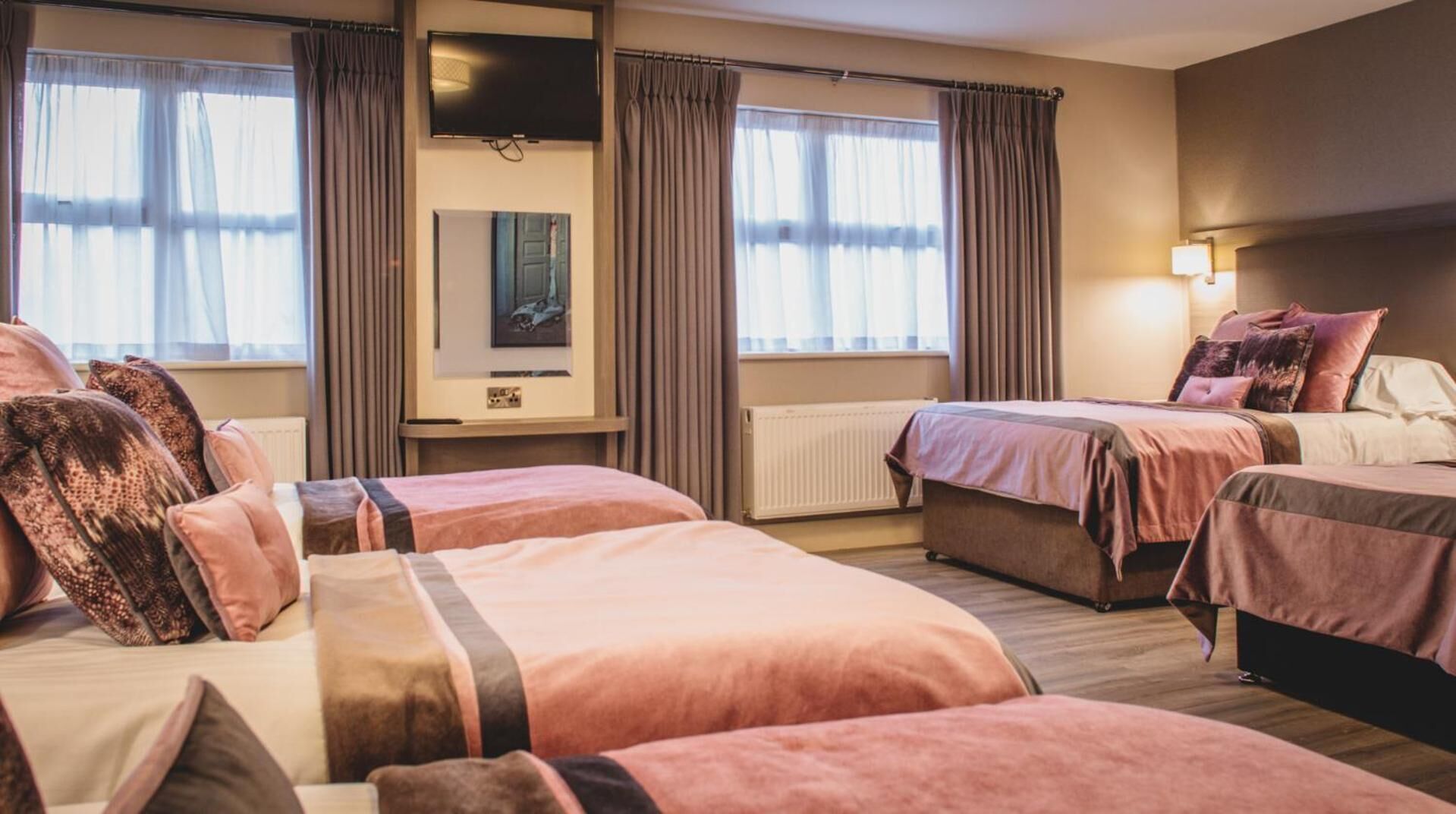 Una habitación de hotel con dos camas, televisión y ventana con cortinas.