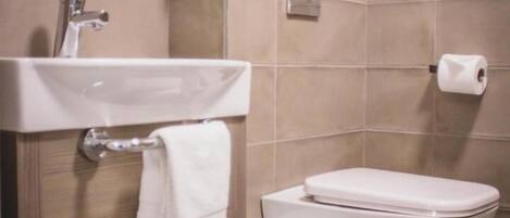 A bathroom with a sink, toilet, and a shelf with toiletries.