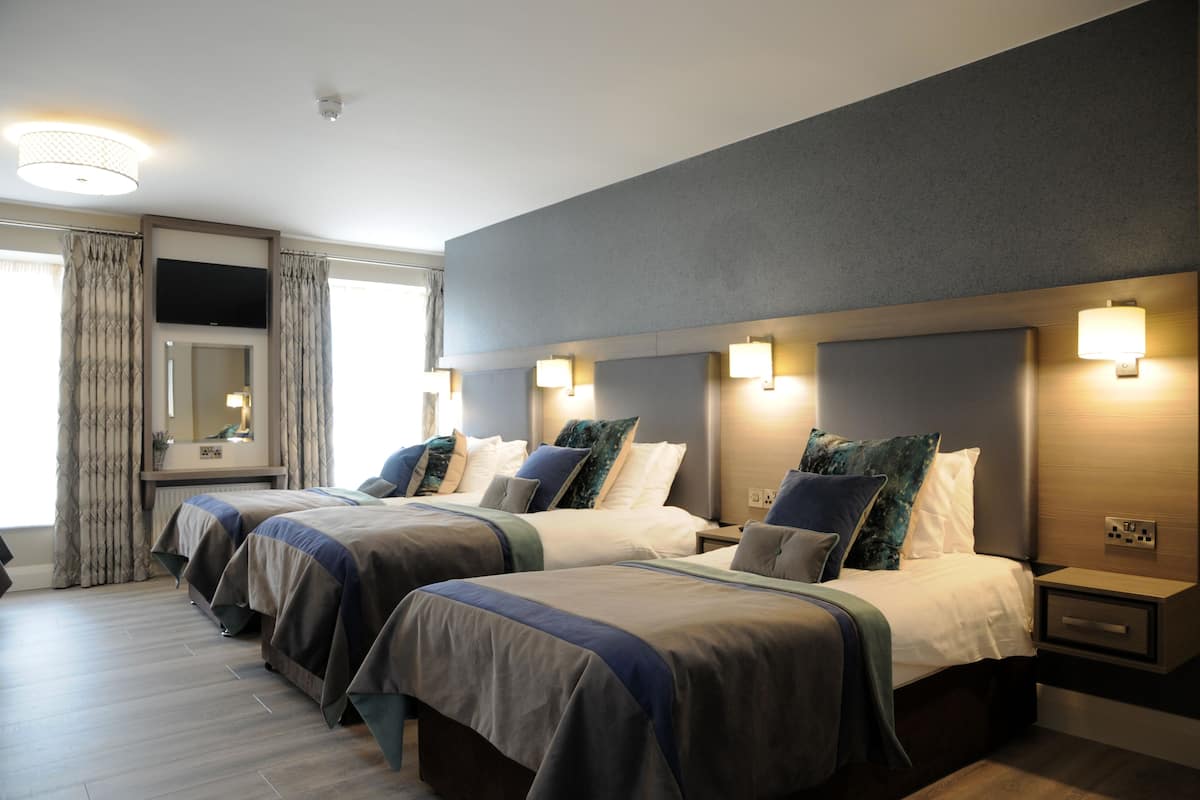 Quarto de hotel com duas camas, televisão de tela plana, abajures e um espelho grande.