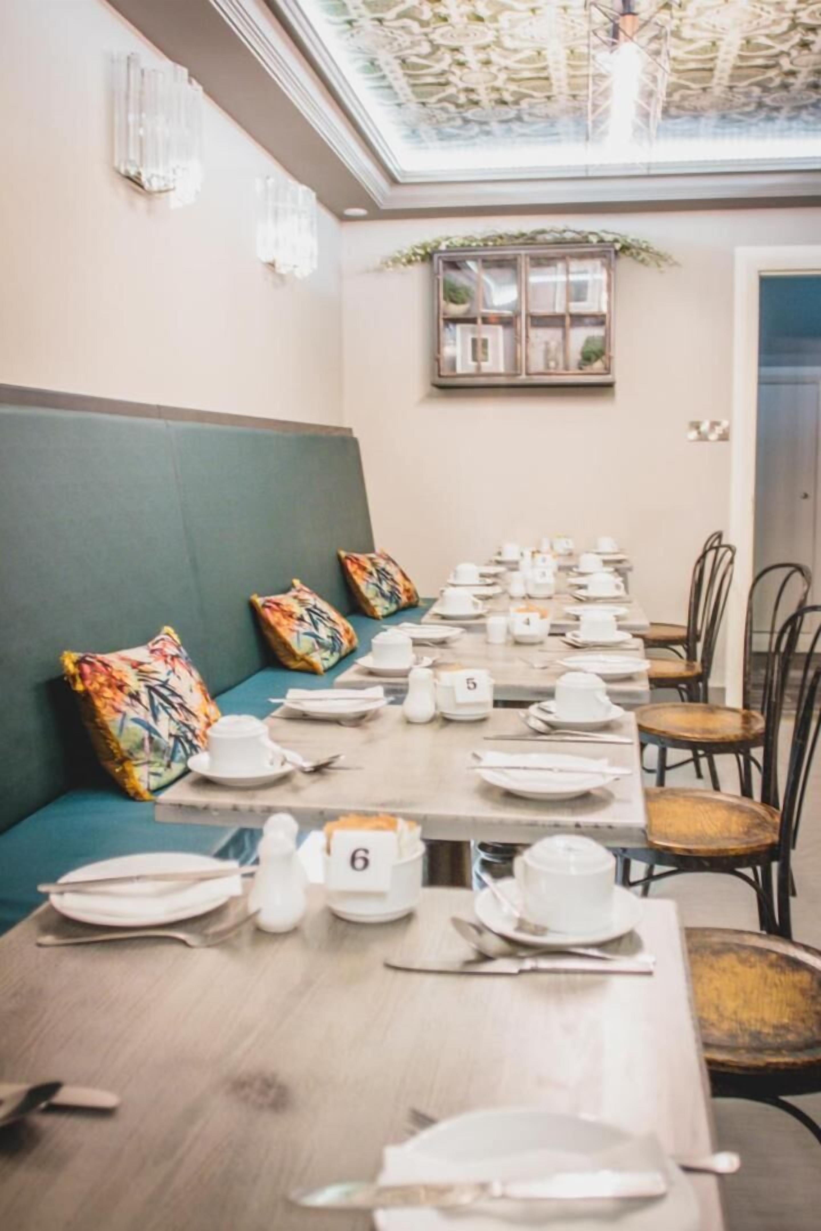 A dining area with a long table set for a meal, numbered seats, and a green cushioned bench.