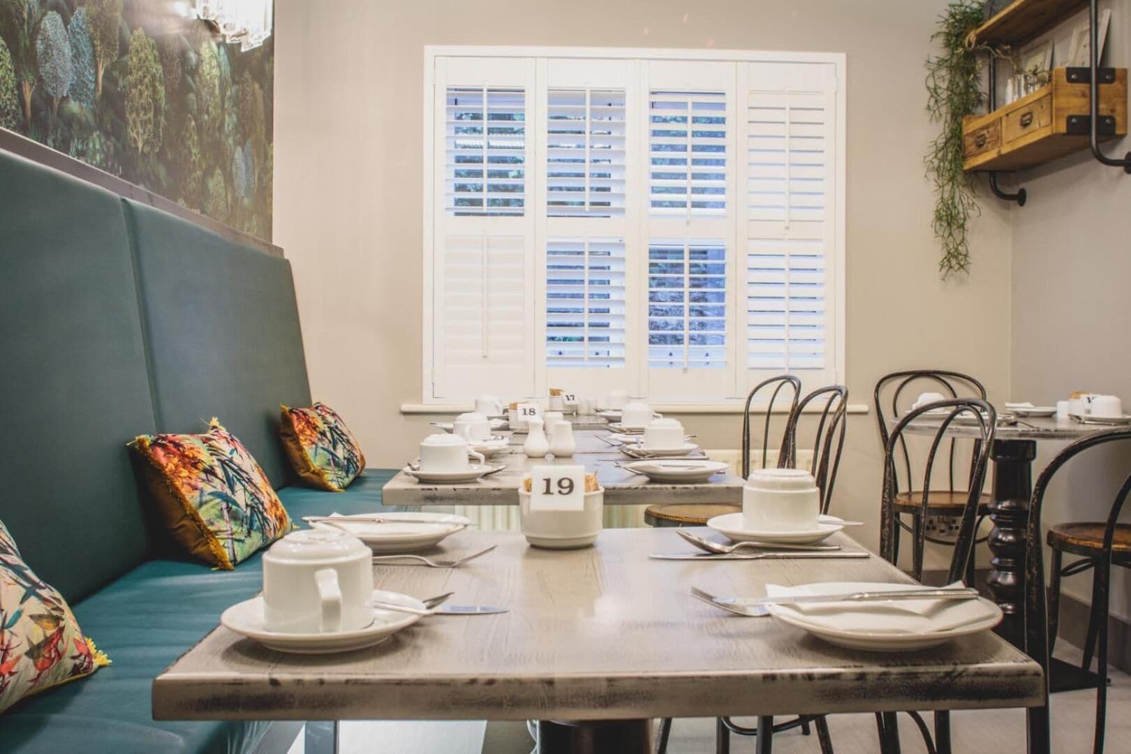 A dining area with tables set for service, numbered seating, and a mural on the wall.