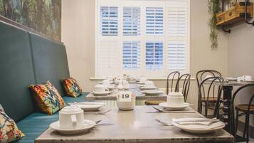 A dining area with tables set for service, numbered seating, and a mural on the wall.