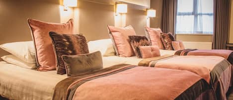 Habitación de hotel con dos camas, cada una con cabeceros y mesitas de noche a juego.