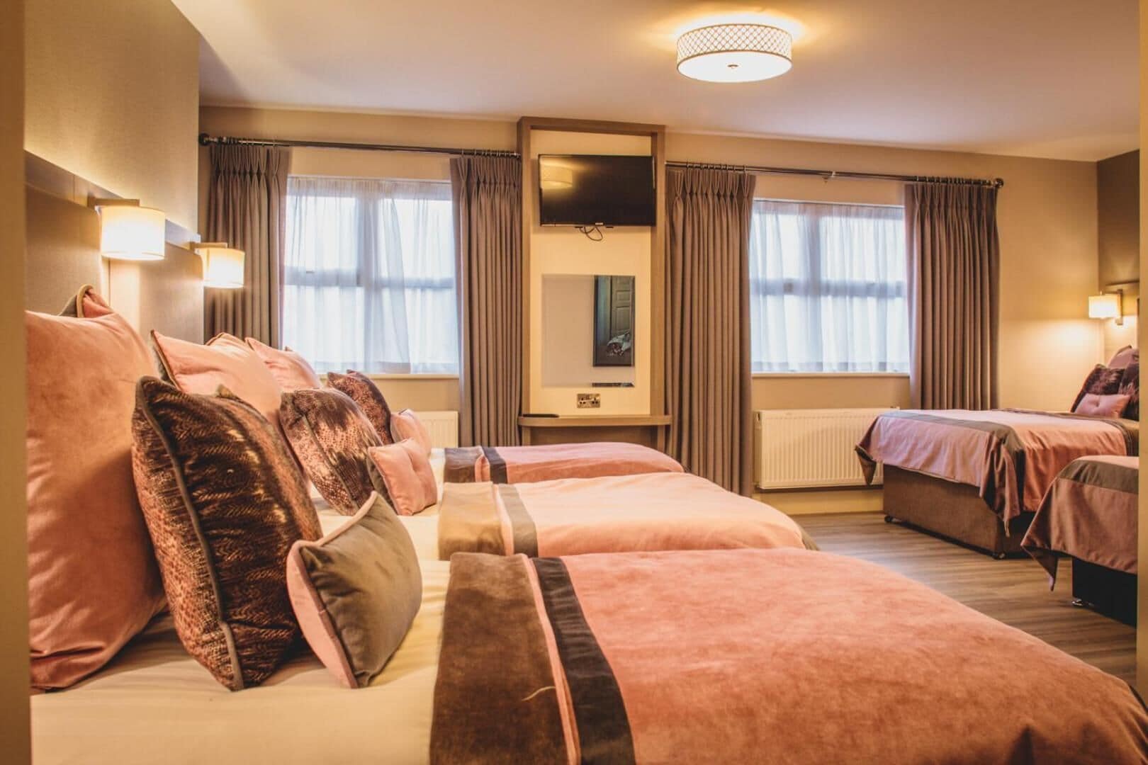 A hotel room with a large bed, a smaller bed, a sofa, and a TV.