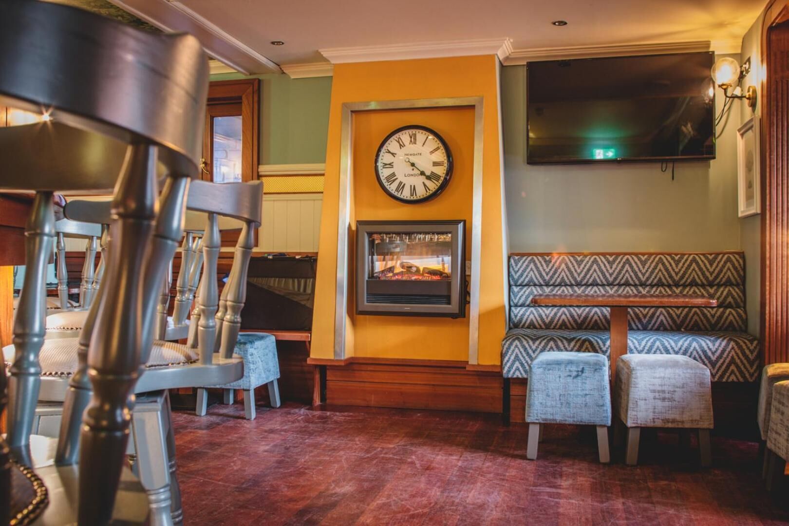 A cozy interior with a vintage clock, a fireplace, and a patterned bench.
