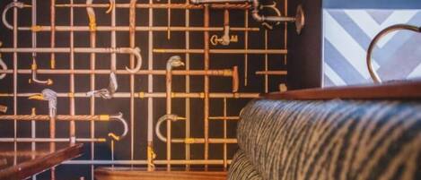 A room with a patterned wall, a wooden stool, and a patterned sofa.