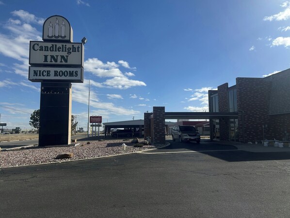 A Candlestick Inn sign with a 'Nice Rooms' banner, a parking area, and a building with a brick facade.
