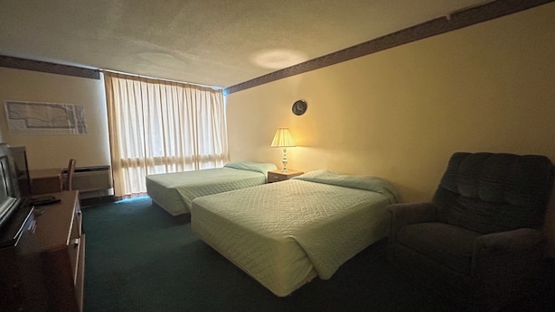 A hotel room with two beds, a desk with a computer, a chair, and a lamp. - Candlelight Inn by Capital O Scottsbluff (Scottsbluff)